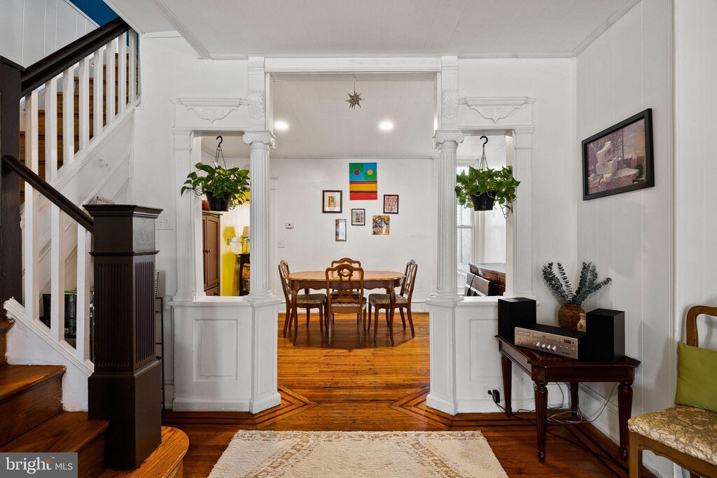 interior space with stairs, wood finished floors, and decorative columns