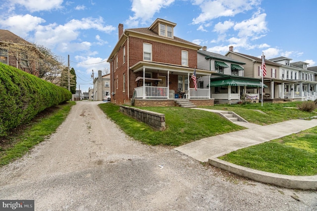 536 S Franklin St, Hanover, PA 17331 - view of front of property with a chimney, dirt driveway, brick siding, a front lawn, and a residential view