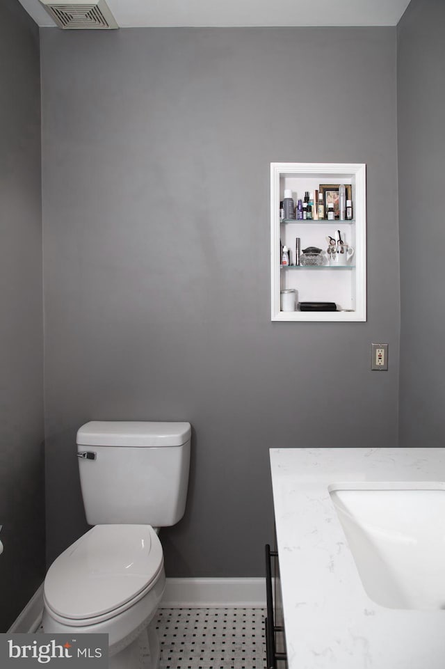 bathroom featuring baseboards, visible vents, toilet, and vanity