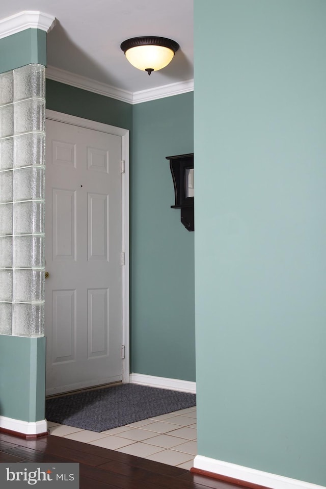 foyer with baseboards, crown molding, and wood finished floors