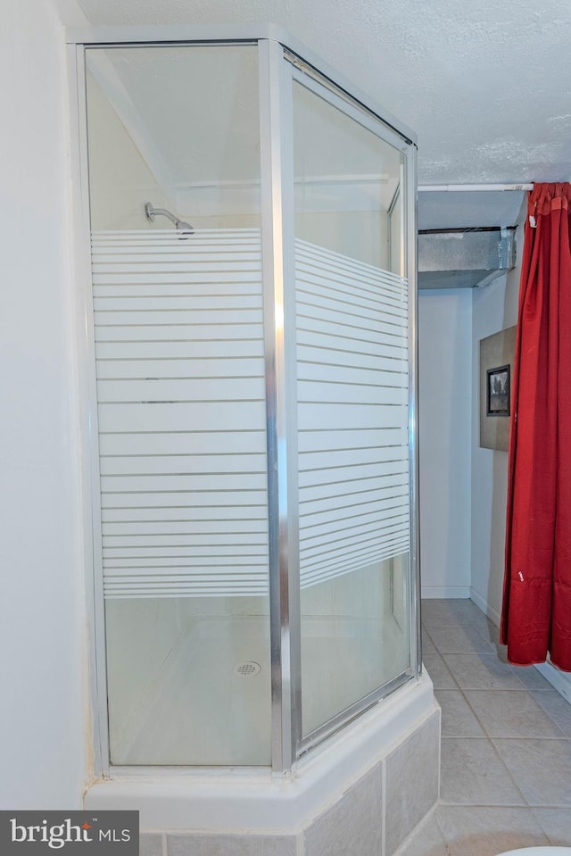 bathroom with a shower stall and tile patterned floors