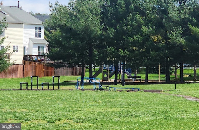 view of property's community with a lawn, fence, and playground community