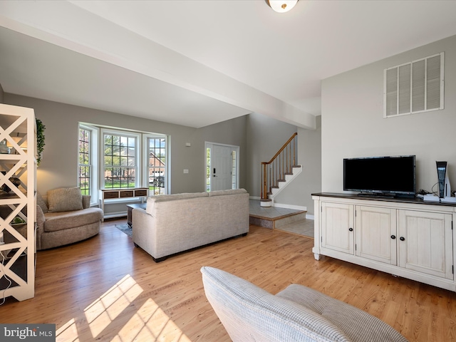 living area with stairs, light wood-style floors, and visible vents