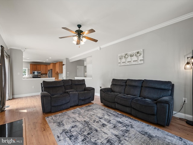 living room with light wood-style flooring, baseboards, a ceiling fan, and crown molding