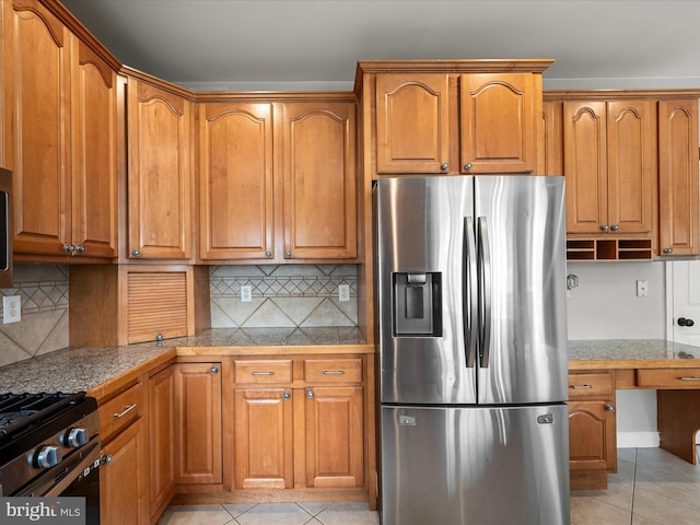 kitchen with light tile patterned floors, brown cabinetry, and appliances with stainless steel finishes