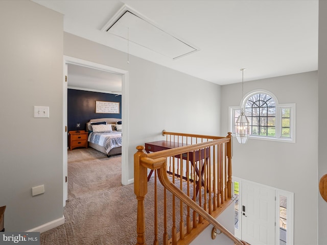 hall with attic access, baseboards, carpet, and an upstairs landing