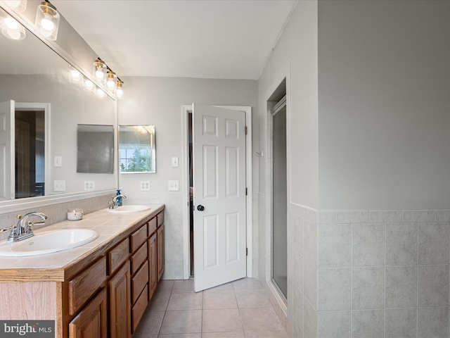 full bathroom with tile walls, a shower stall, a sink, and tile patterned flooring