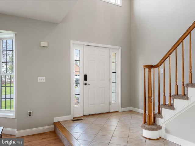 foyer entrance featuring plenty of natural light, a high ceiling, and stairway