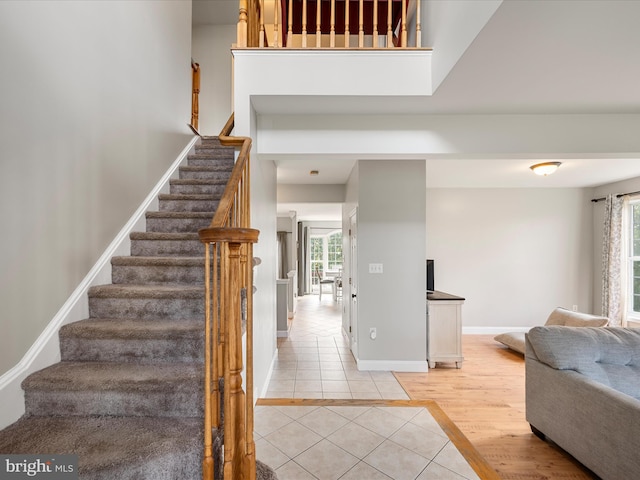 staircase featuring tile patterned floors, baseboards, and a healthy amount of sunlight