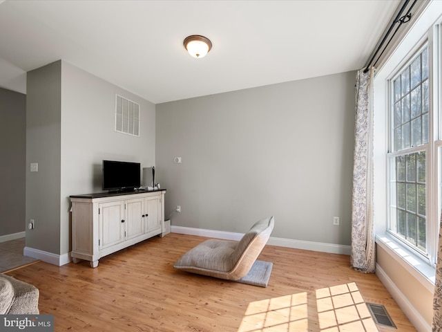 living area featuring light wood-style flooring, visible vents, and baseboards