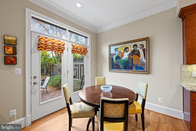 dining space with baseboards, ornamental molding, and light wood finished floors