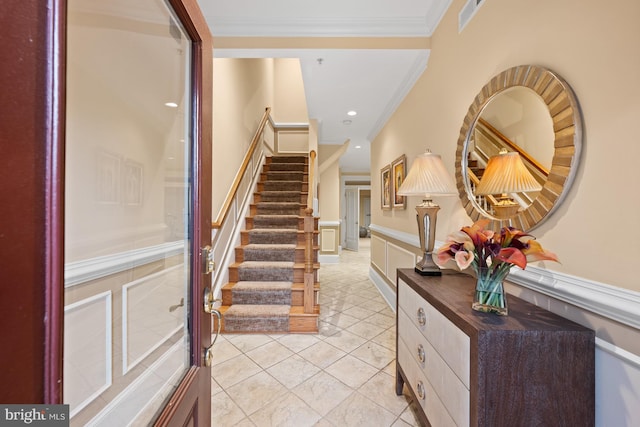 entrance foyer with crown molding, stairway, recessed lighting, a decorative wall, and wainscoting