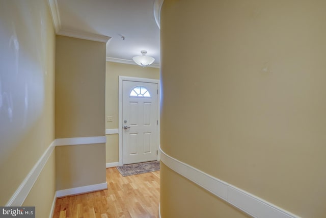 entryway with ornamental molding, baseboards, and light wood-style floors
