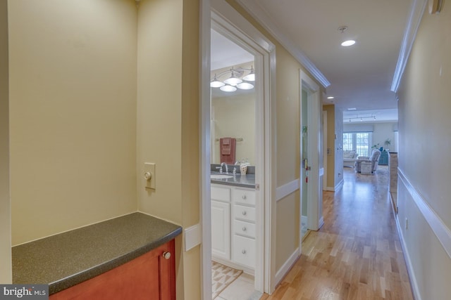 hall featuring recessed lighting, ornamental molding, light wood-style flooring, and a sink