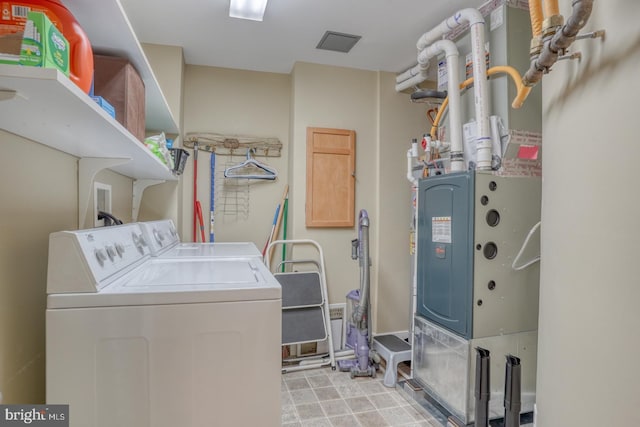 washroom with washer and dryer, heating unit, visible vents, and laundry area