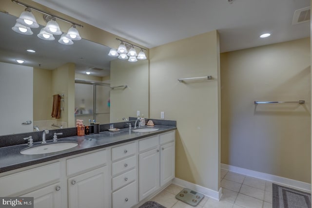 bathroom featuring tile patterned floors, double vanity, a stall shower, and a sink