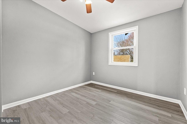 spare room featuring a ceiling fan, baseboards, and wood finished floors