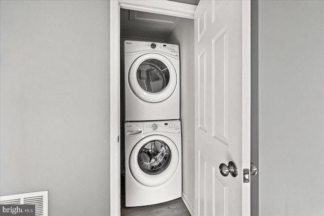 clothes washing area with stacked washer / dryer, laundry area, and wood finished floors