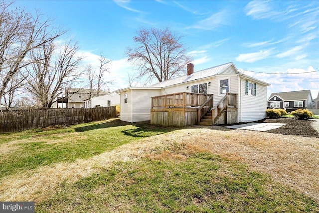 back of house featuring stairs, fence, a wooden deck, a yard, and a chimney