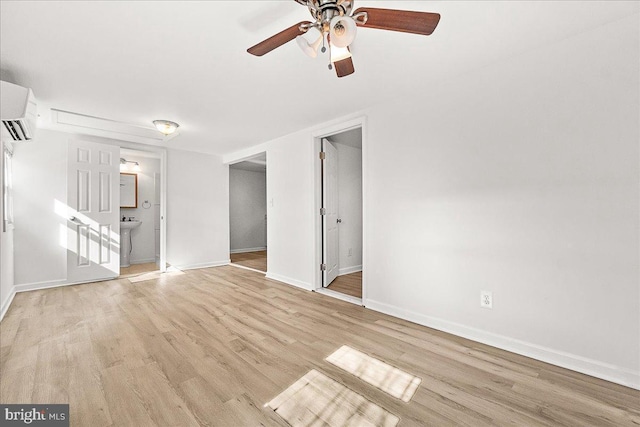 interior space featuring a sink, a ceiling fan, wood finished floors, baseboards, and an AC wall unit