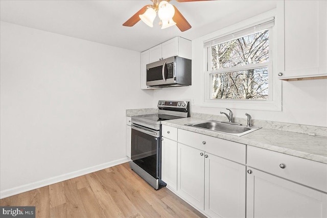 kitchen featuring a sink, appliances with stainless steel finishes, light wood-type flooring, baseboards, and ceiling fan