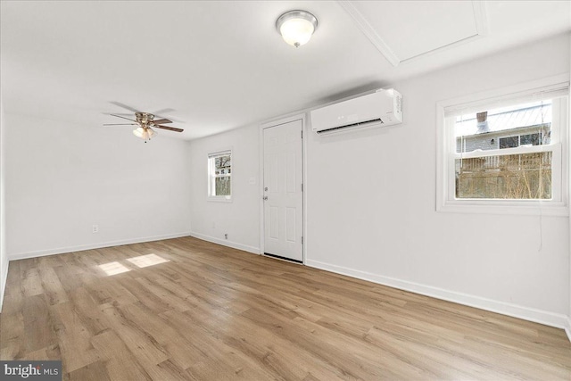 unfurnished room featuring a wall mounted air conditioner, baseboards, a ceiling fan, and light wood finished floors