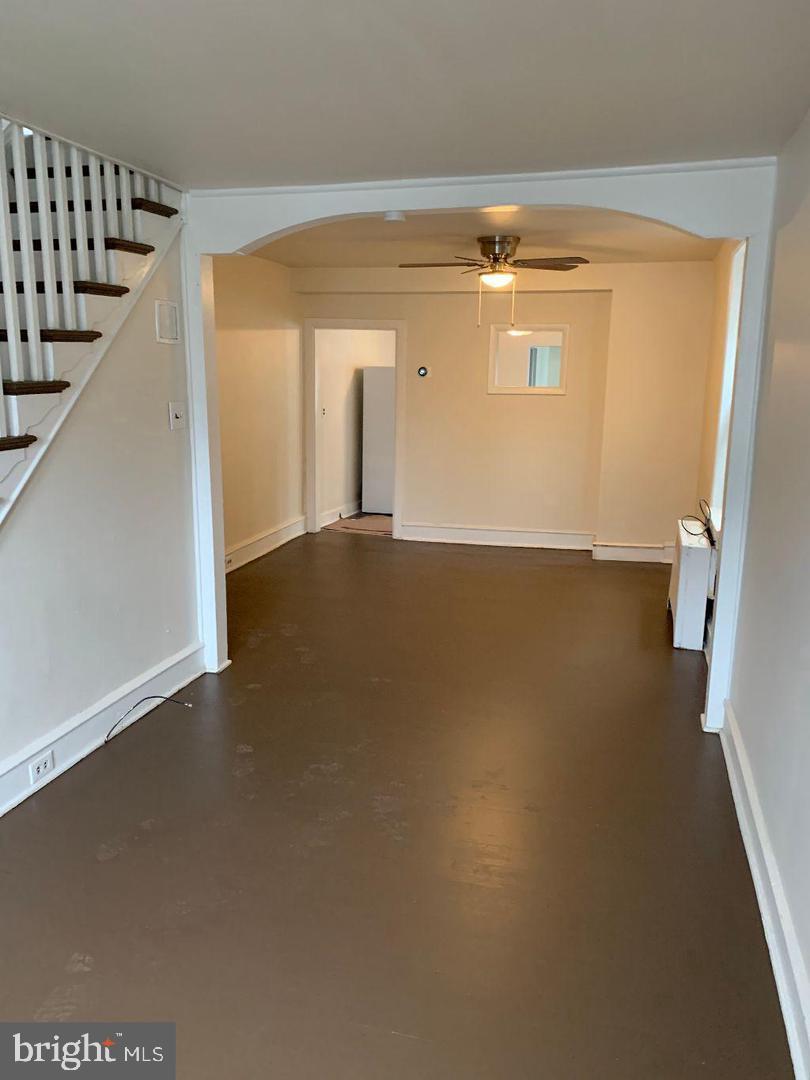 unfurnished living room featuring arched walkways, baseboards, and a ceiling fan
