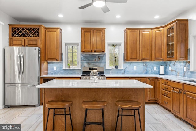 kitchen with brown cabinetry, appliances with stainless steel finishes, and a breakfast bar area