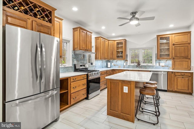 kitchen featuring tasteful backsplash, brown cabinets, under cabinet range hood, and stainless steel appliances