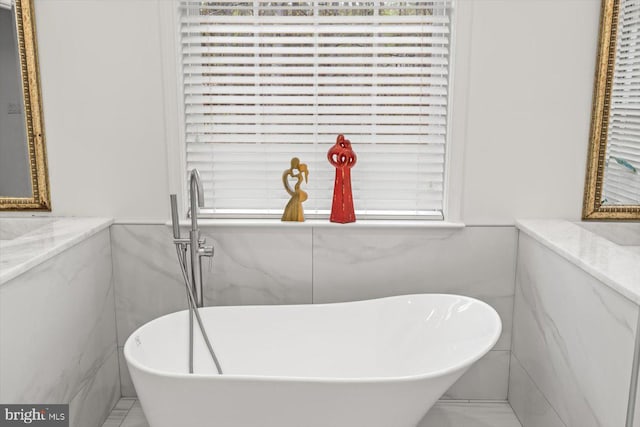full bathroom with wainscoting, tile walls, and a soaking tub