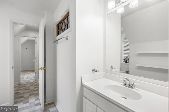 bathroom with tile patterned floors, vanity, baseboards, and lofted ceiling
