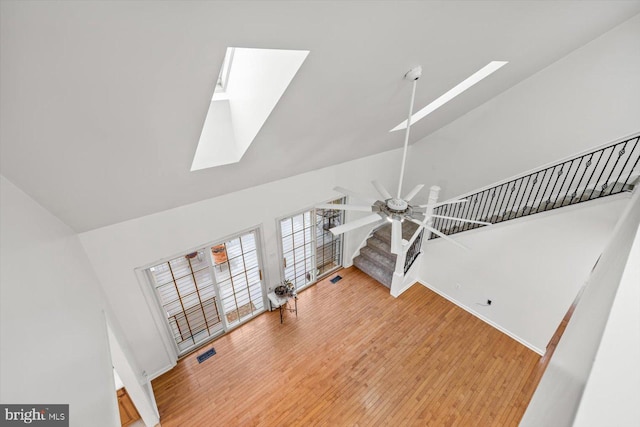 unfurnished living room featuring visible vents, a skylight, wood finished floors, and baseboards