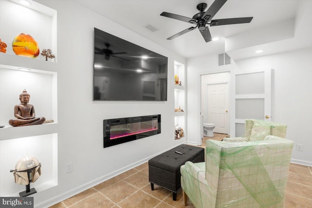 tiled living room featuring a glass covered fireplace, visible vents, and a ceiling fan