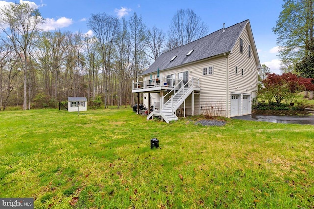 rear view of house with aphalt driveway, stairs, a garage, a yard, and a deck