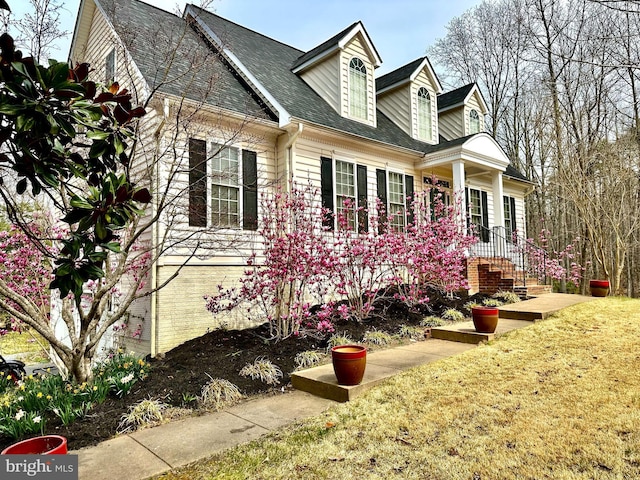 view of side of property with roof with shingles and a lawn