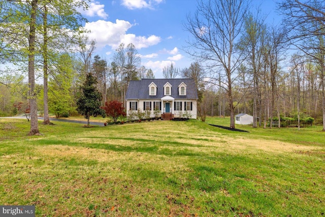 cape cod-style house featuring roof with shingles, covered porch, and a front yard