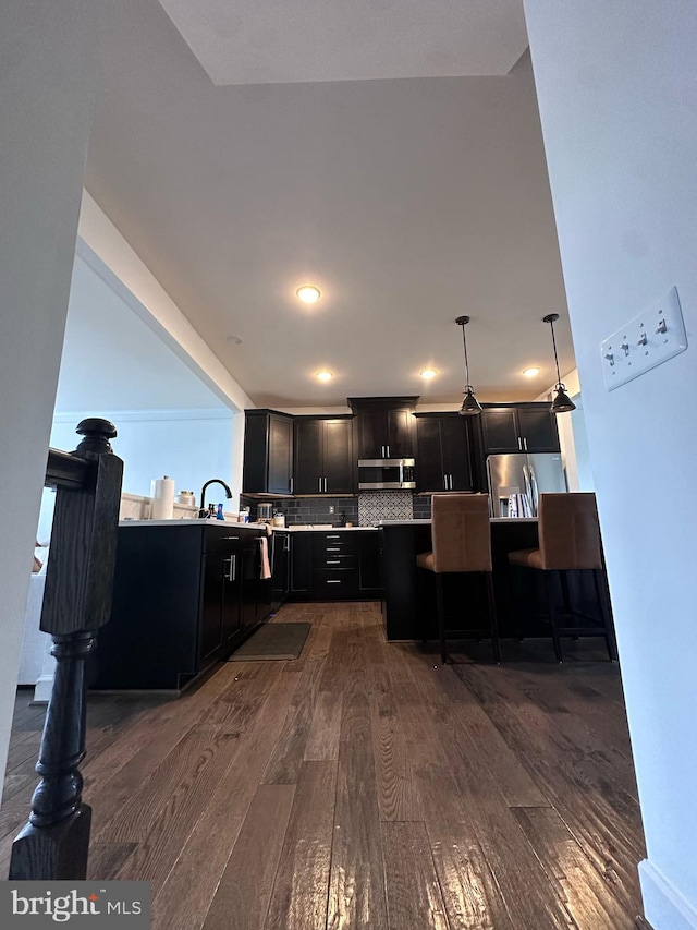 8676 Underhill Ln, Manassas, VA 20112 - kitchen featuring stainless steel appliances, a peninsula, dark wood-style floors, and dark cabinetry
