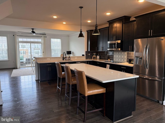 8676 Underhill Ln, Manassas, VA 20112 - kitchen featuring a center island, a sink, light countertops, appliances with stainless steel finishes, and decorative backsplash
