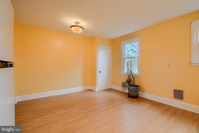 spare room with wood finished floors, baseboards, and visible vents