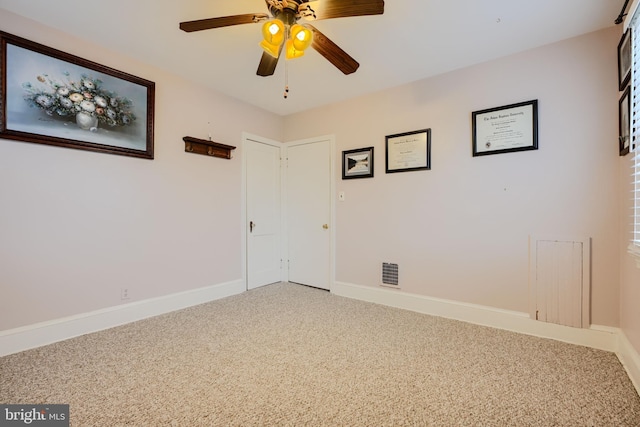 carpeted empty room featuring visible vents, baseboards, and a ceiling fan