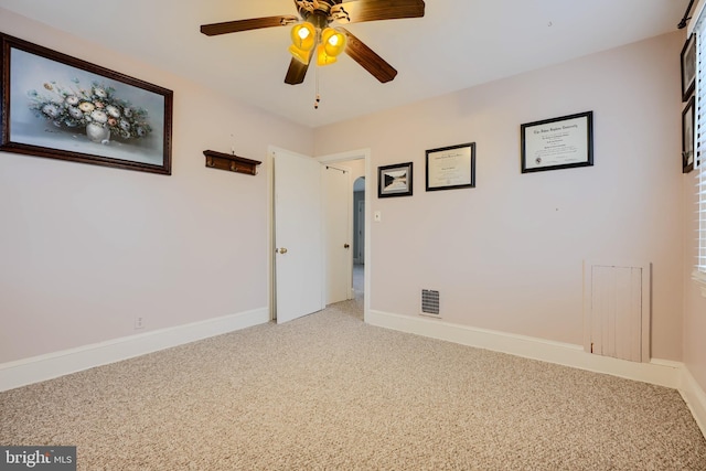 carpeted spare room with visible vents, baseboards, and ceiling fan