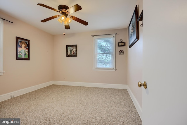 carpeted spare room featuring baseboards and a ceiling fan