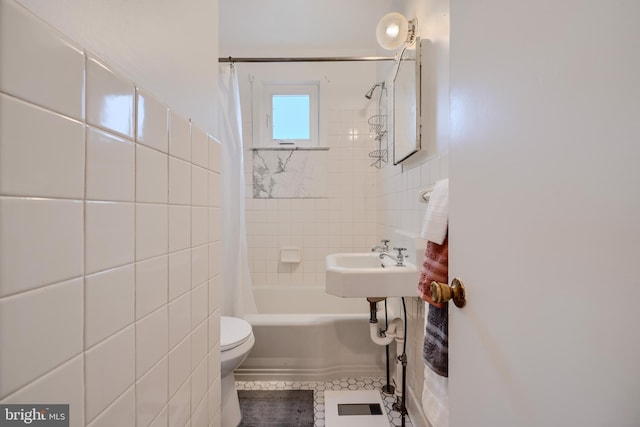 bathroom featuring tile walls, toilet, and shower / bath combo with shower curtain
