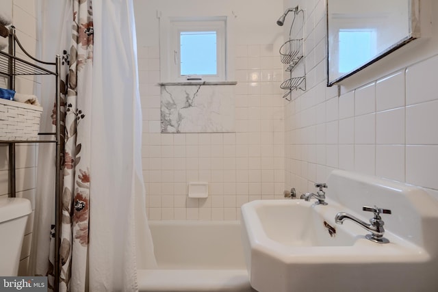 full bathroom featuring toilet, shower / bath combo with shower curtain, and tile walls