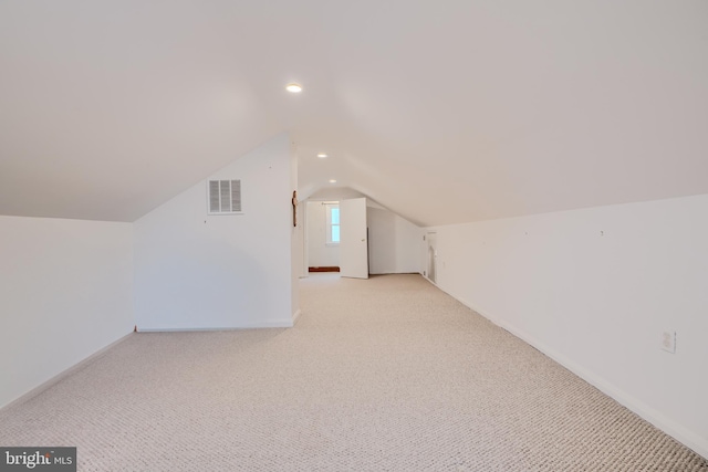 additional living space featuring visible vents, baseboards, vaulted ceiling, and light carpet