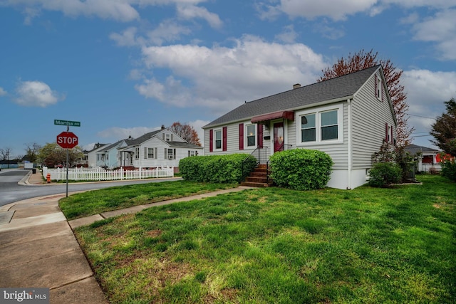 bungalow with a shingled roof, a front yard, and fence