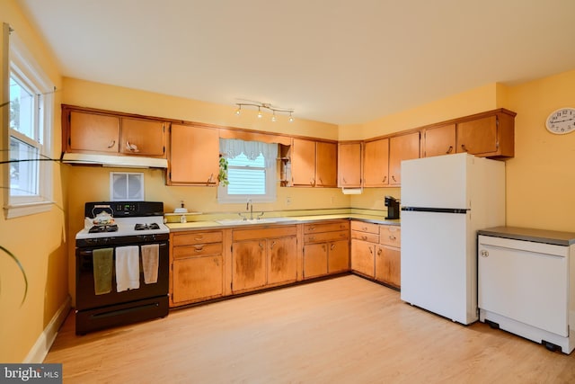 kitchen featuring white appliances, light wood-type flooring, under cabinet range hood, light countertops, and a sink