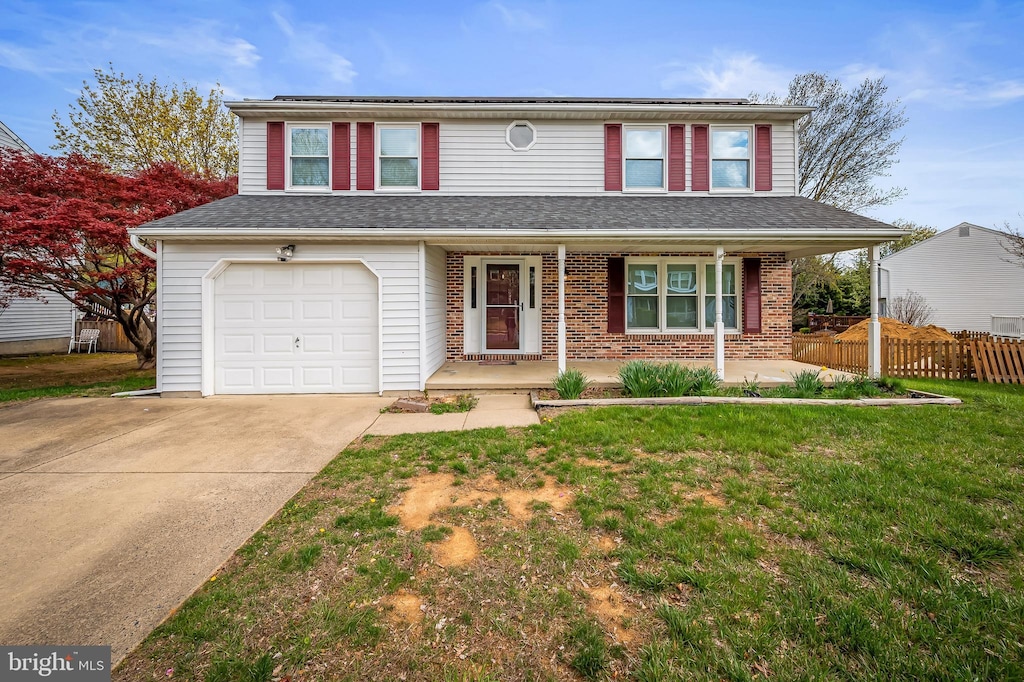traditional-style home with concrete driveway, fence, a porch, a front yard, and a garage
