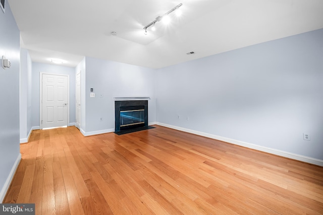 922 Fell St, Baltimore, MD 21231 - unfurnished living room featuring light wood-style floors, track lighting, a fireplace with flush hearth, visible vents, and baseboards