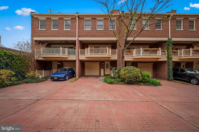 922 Fell St, Baltimore, MD 21231 - view of front of house with a garage, brick siding, driveway, and a chimney
